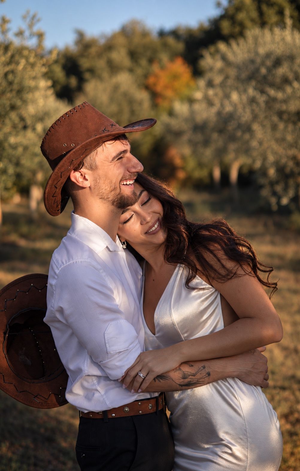 A couple embracing among the olive trees in the late afternoon light